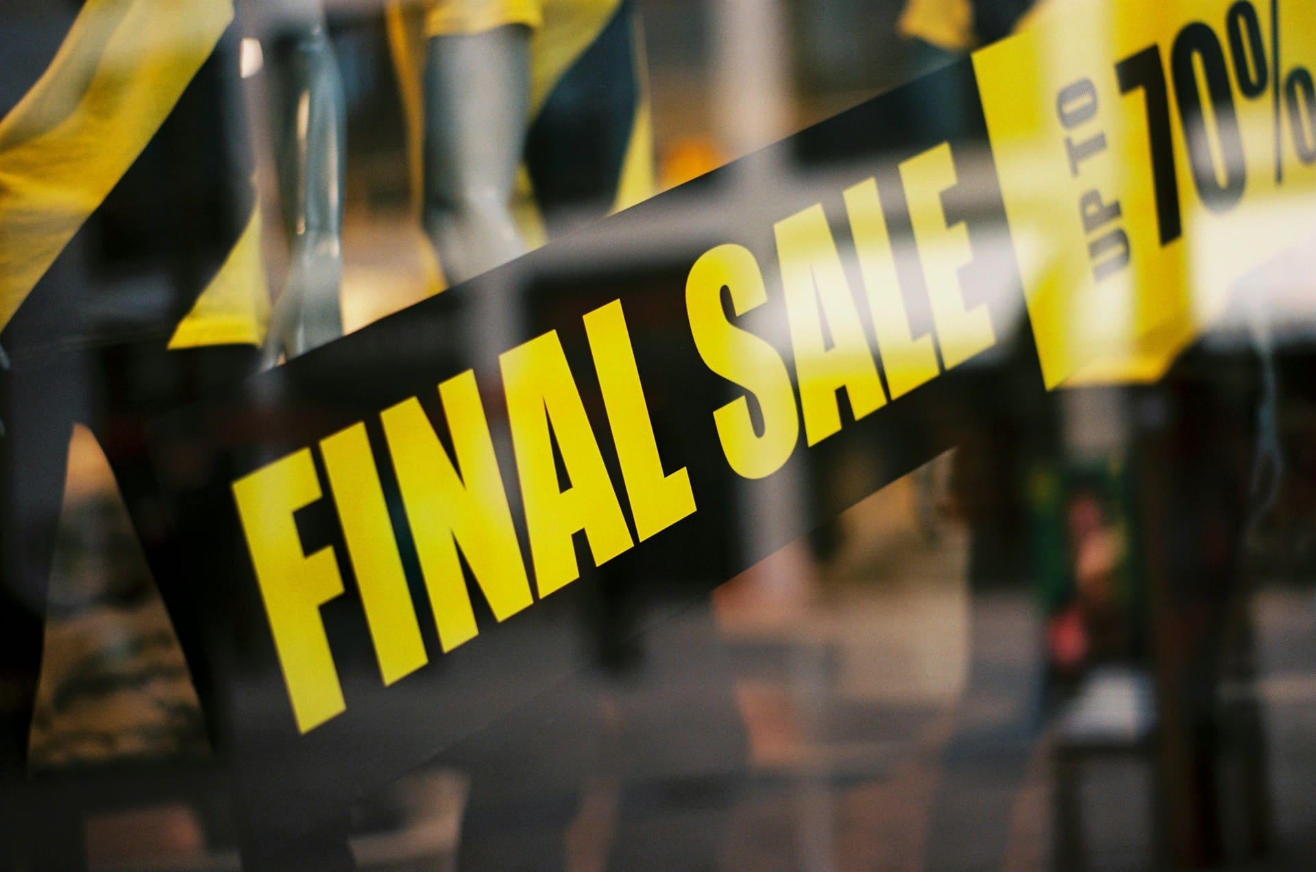 Close-up view of a banner on a store window in yellow and black, saying