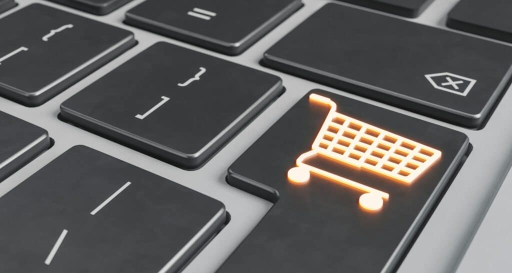 Close up of a computer keyboard with a key featuring an illuminated shopping card icon, representing e-commerce and online fraud